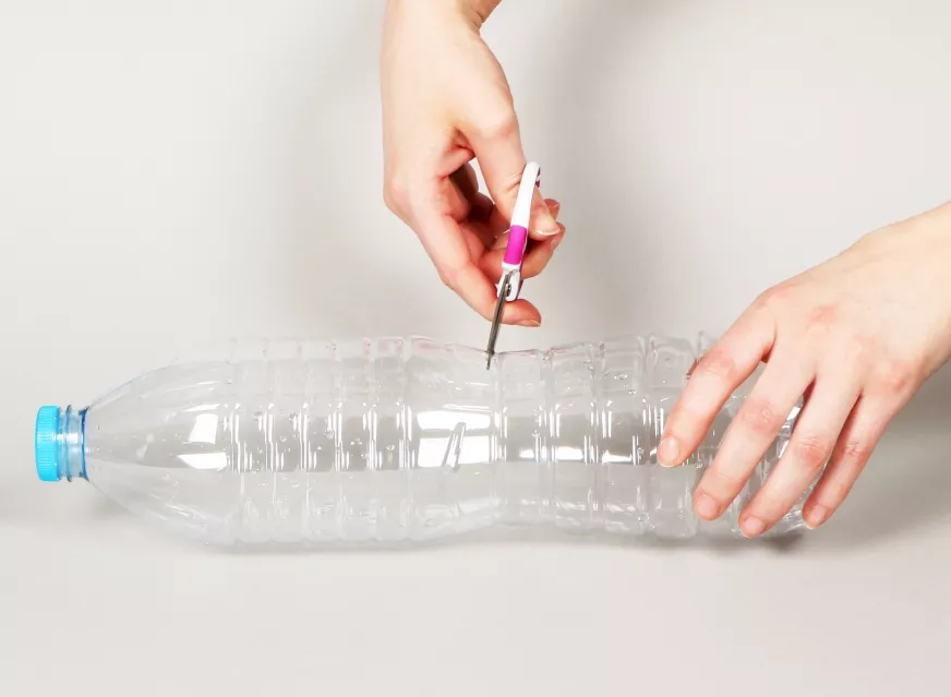 Cómo cortar una botella de agua de plástico con unas tijeras para construir una clepsidra.